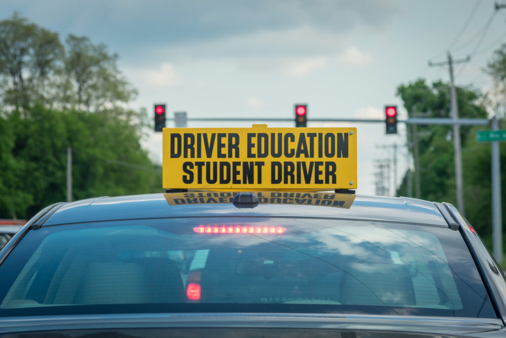 Student driver sign on top of car at stoplight